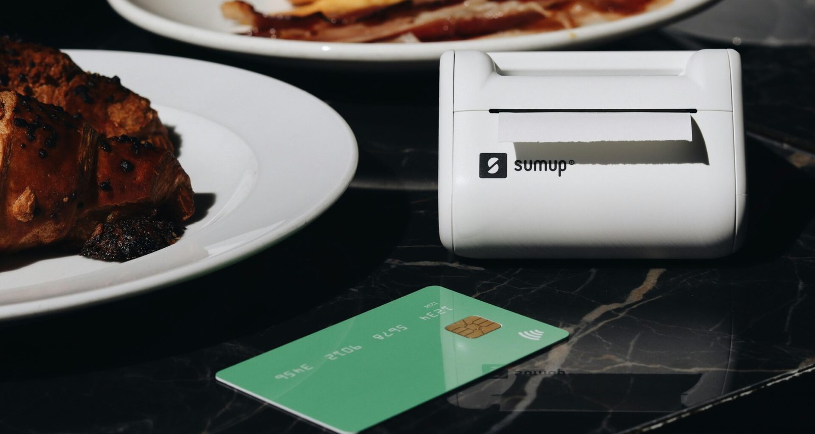 Ein gedeckter Tisch mit mehreren Tellern voller Speisen und einer Kreditkarte, die auf dem Tisch liegt.