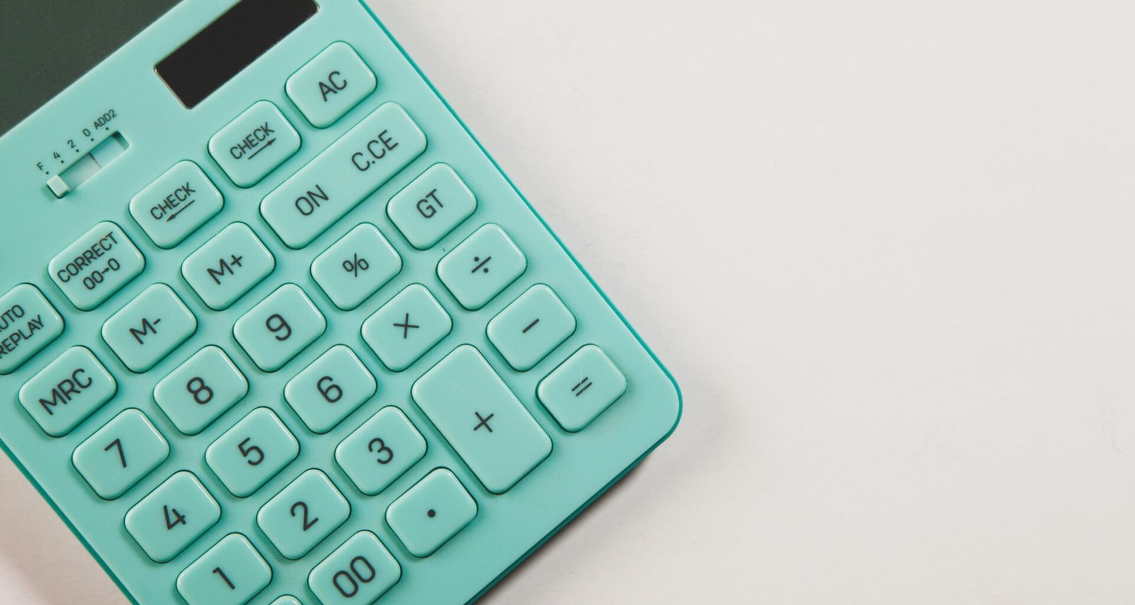 Türkisfarbener Taschenrechner auf einer weißen Oberfläche, neutral arrangiert für technische und wirtschaftliche Themen