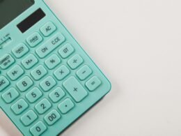 Türkisfarbener Taschenrechner auf einer weißen Oberfläche, neutral arrangiert für technische und wirtschaftliche Themen