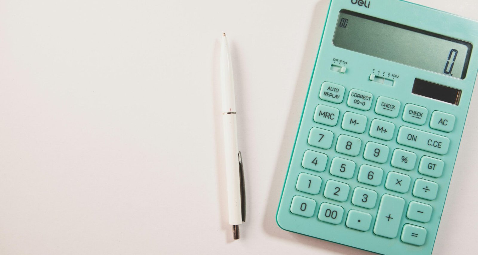 Ein türkisfarbener Taschenrechner neben einem weißen Stift auf weißem Hintergrund, geeignet für Themen wie Finanzen oder Online-Tools.