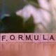 Scrabble-Steine auf einem Holztisch bilden das Wort Formel, Symbol für Strategie und Planung im Online-Marketing