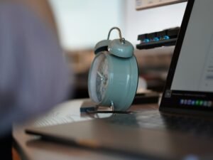 Ein analoger Wecker steht auf einem Laptop und symbolisiert Zeitmanagement am Arbeitsplatz