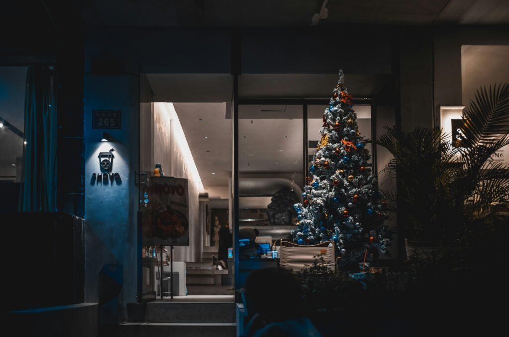 Ein Weihnachtsbaum mit Lichtern steht als einzige Lichtquelle in einem dunklen Raum