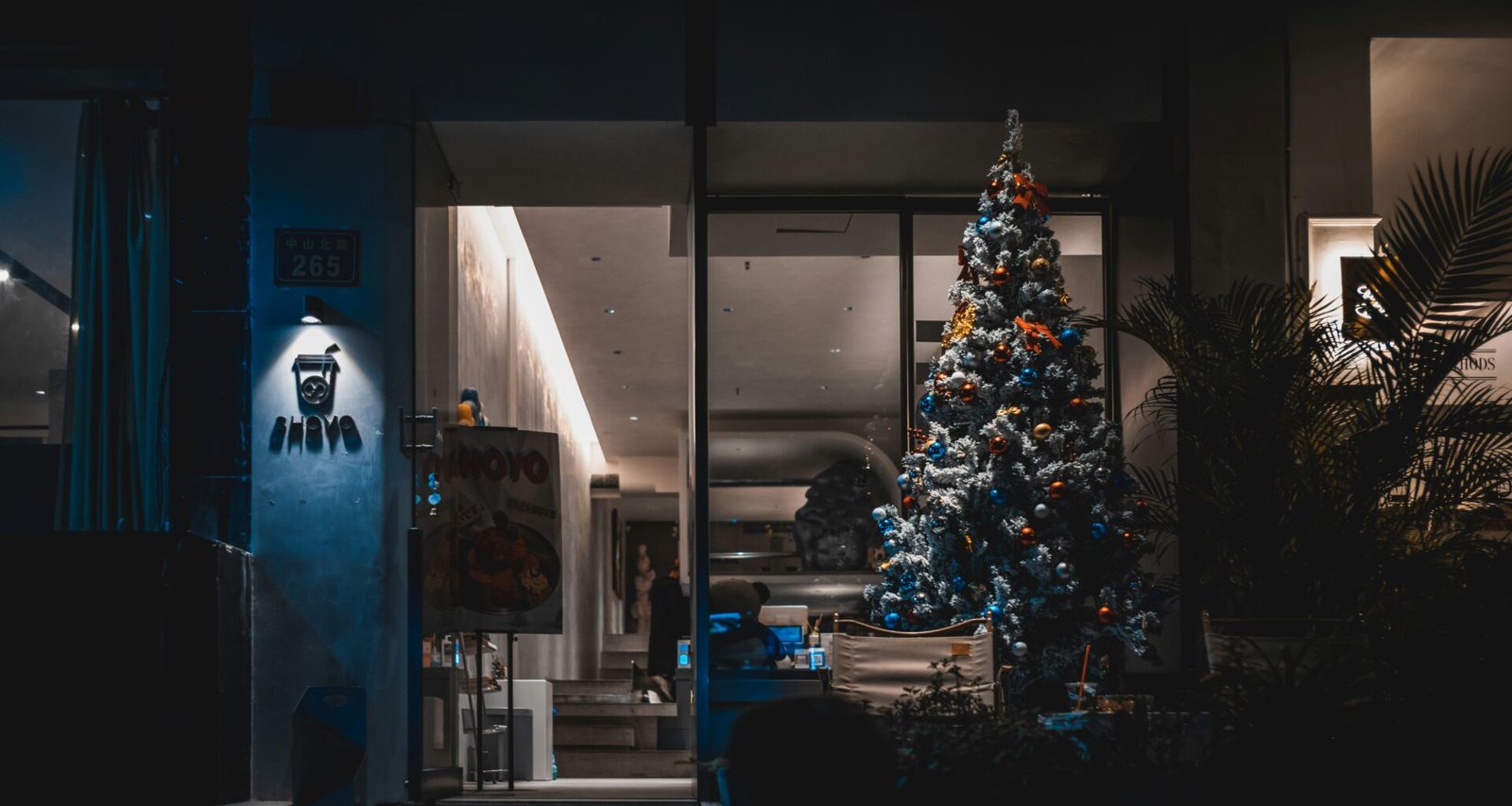 Ein Weihnachtsbaum mit Lichtern steht als einzige Lichtquelle in einem dunklen Raum