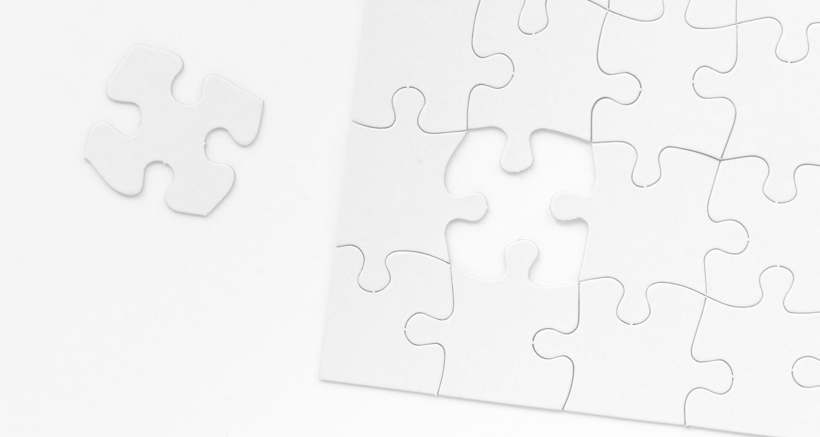 Ein weißes Puzzleteil liegt mittig auf einer glatten Tischoberfläche – Symbol für Zusammenhänge in der digitalen Welt.