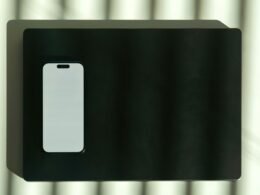 Ein weißes Smartphone wird quer auf einer schwarzen Oberfläche dargestellt – Symbol für moderne Technologie.