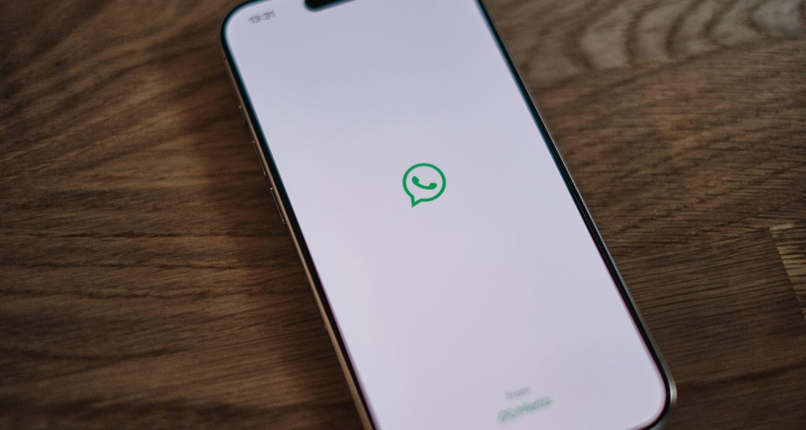Ein weißes Smartphone mit einer grünen Textnachricht auf dem Bildschirm vor neutralem Hintergrund, Fokus auf mobiler Kommunikation.