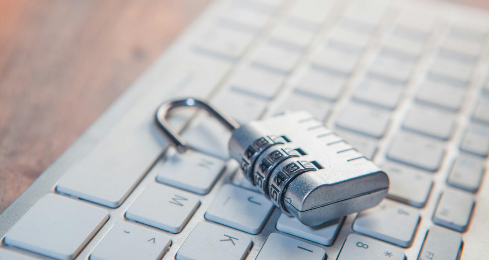 Ein silbernes Zahlenschloss ruht auf den Tasten einer Computertastatur und symbolisiert digitale Sicherheit