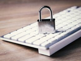 Nahaufnahme einer Computer-Tastatur, auf der ein silbernes Vorhängeschloss liegt, Symbol für IT-Sicherheit und Datenschutz