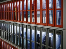 Eine Gebäudefassade mit einer Wand aus Fenstern, die von auffälligen roten Rahmen eingefasst werden.