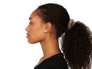 Junge Frau mit zusammengebundenen Haaren zu einem Pferdeschwanz, fotografiert von der Seite.