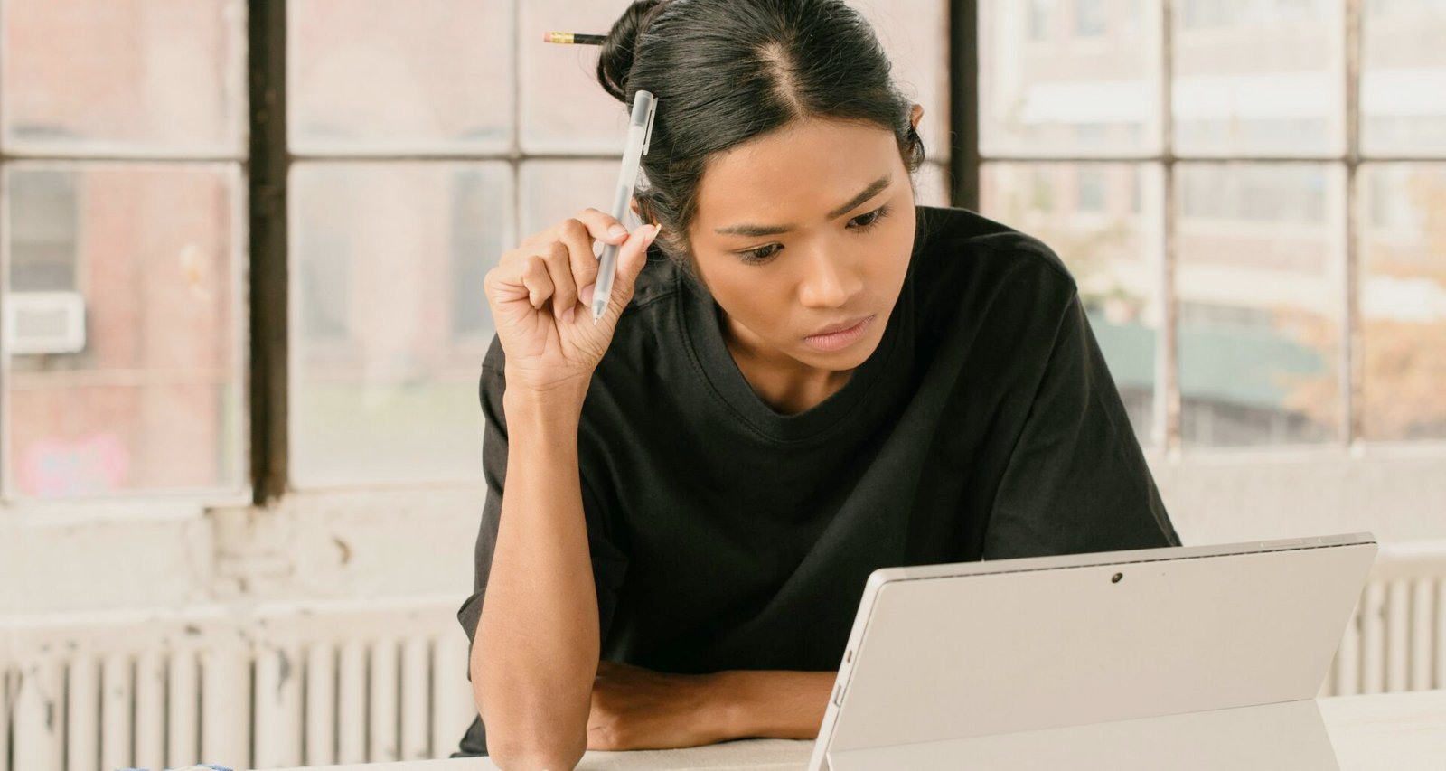 Eine Frau sitzt an einem Tisch und verwendet einen Laptop, typische Arbeitsszene aus dem Homeoffice.