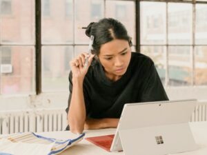 Frau sitzt an einem Tisch und arbeitet konzentriert an ihrem Laptop in einer modernen Umgebung
