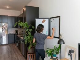 Eine Frau steht in einer modernen Küche vor einem geöffneten Kühlschrank, Fokus auf Küchentechnologie