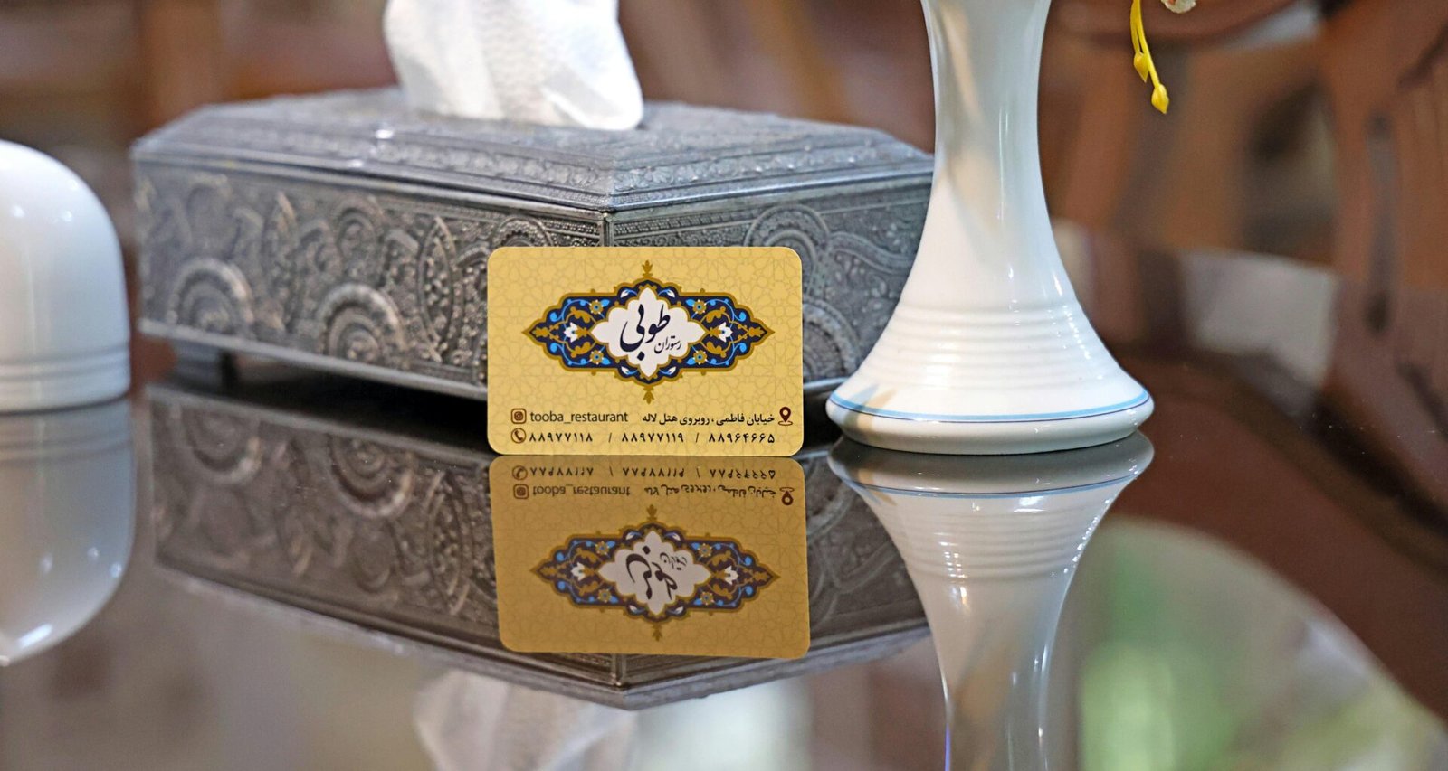 Goldene Visitenkarte mit kunstvollem Muster liegt auf einem Tisch, Nahaufnahme eines exklusiven Karten-Designs.