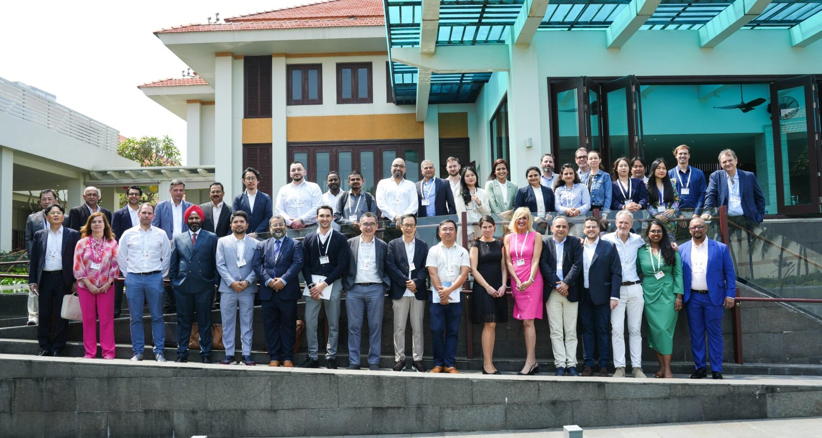 Große Menschengruppe steht tagsüber im Freien vor einem Gebäude und unterhält sich gemeinsam