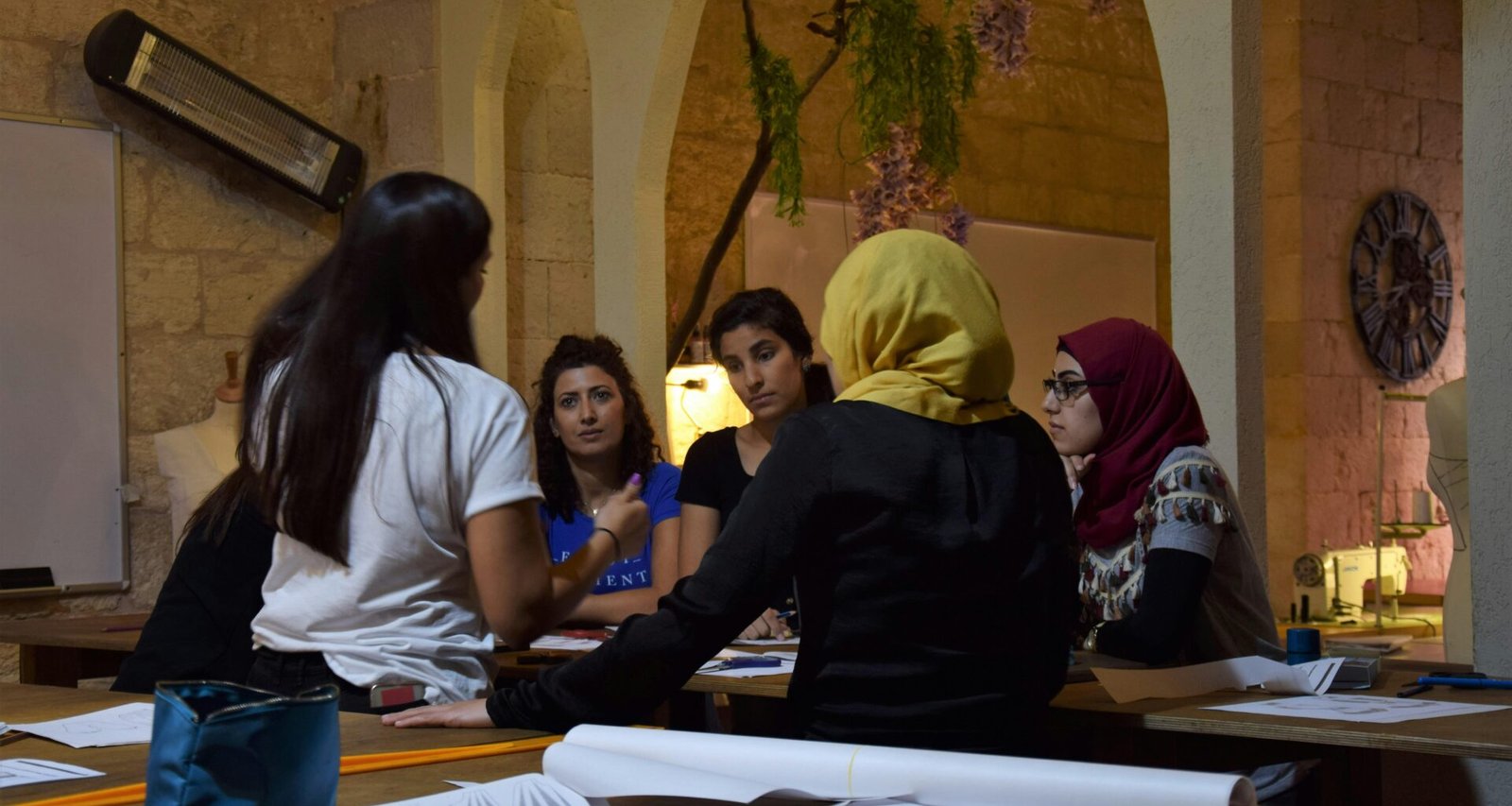Mehrere Frauen sitzen zusammen an einem Tisch und führen eine intensive Gruppendiskussion in einem modernen Arbeitsumfeld.