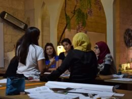 Mehrere Frauen sitzen zusammen an einem Tisch und führen eine intensive Gruppendiskussion in einem modernen Arbeitsumfeld.