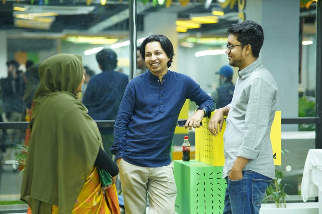 Mehrere Personen stehen um einen grünen Tisch in einem modernen Büro und arbeiten gemeinsam an einem Projekt.