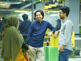 Mehrere Personen stehen um einen grünen Tisch in einem modernen Büro und arbeiten gemeinsam an einem Projekt.