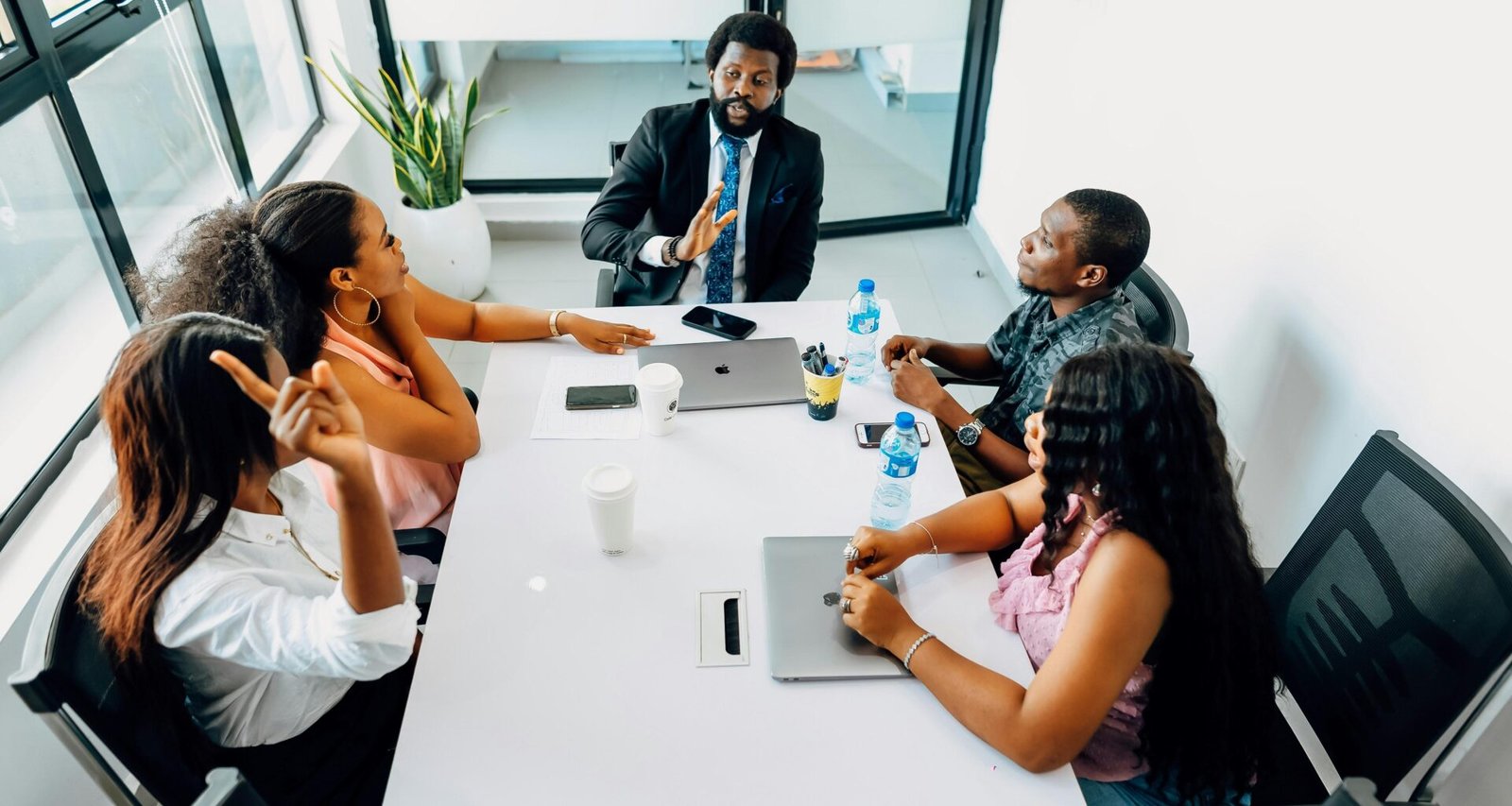 Gruppenbesprechung an einem weißen Tisch mit mehreren Personen – Teamarbeit und Austausch im modernen Umfeld.