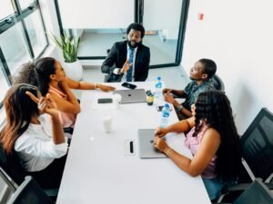 Gruppenbesprechung an einem weißen Tisch mit mehreren Personen – Teamarbeit und Austausch im modernen Umfeld.