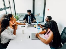 Mehrere Personen sitzen um einen weißen Tisch und besprechen gemeinsam Ideen während eines Meetings im Büro.