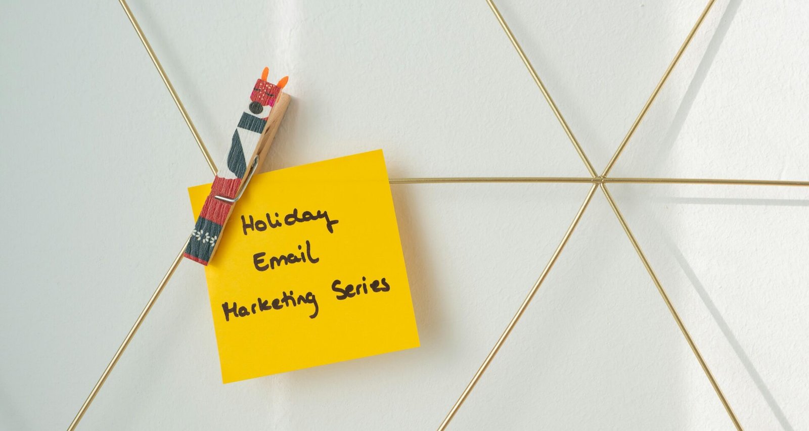 Ein gelber Haftnotizzettel ist mit einem Kugelschreiber an einer hellen Wand befestigt, Symbol für Arbeitsorganisation.