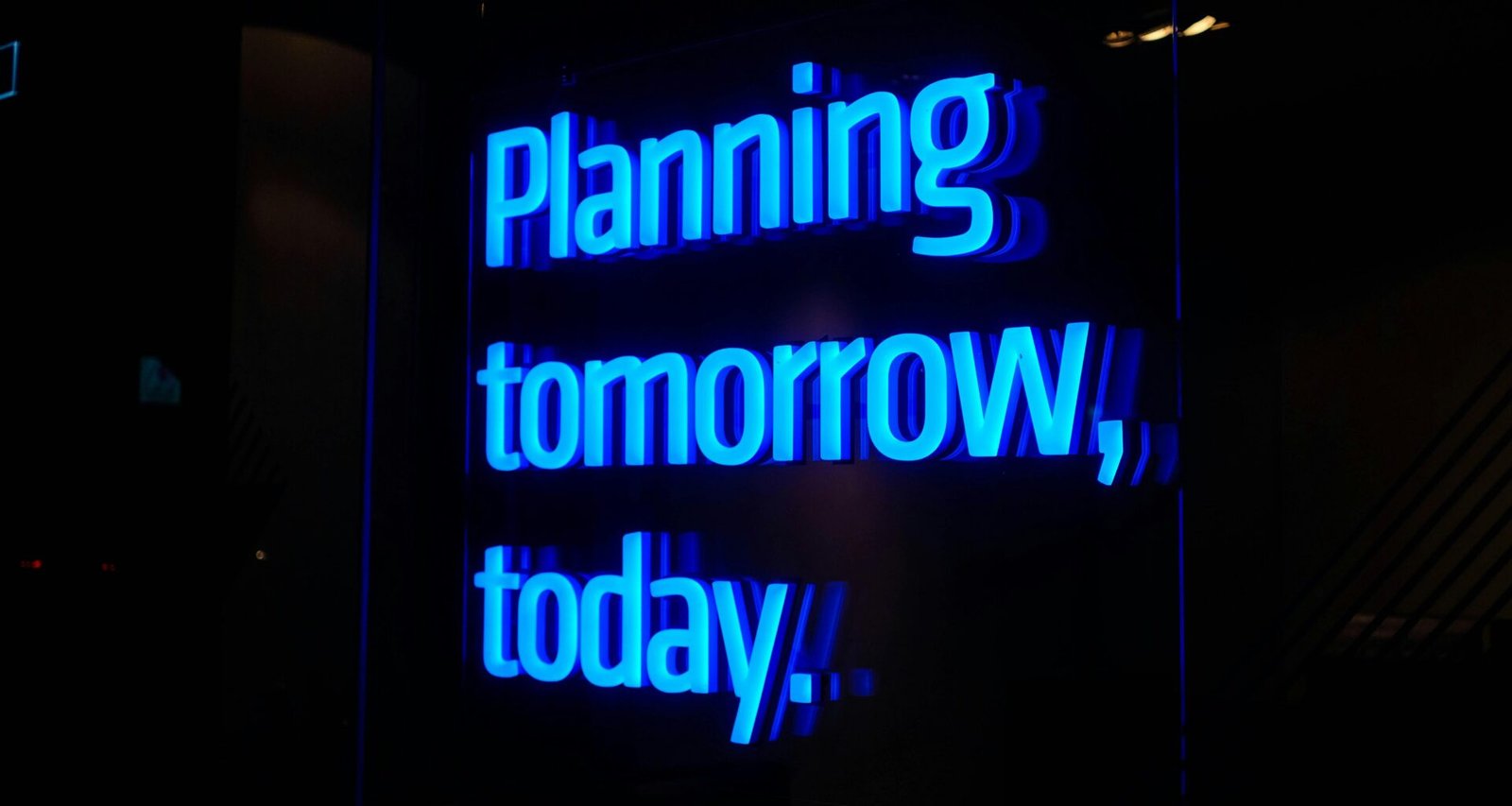 Leuchtendes Neon-Schild mit dem Schriftzug 'Planning tomorrow, today' vor dunklem Hintergrund