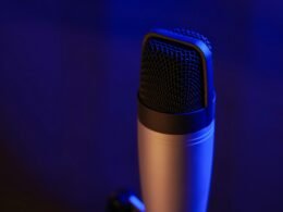 Nahaufnahme eines Mikrofons in einem dunklen Raum, geeignet für Artikel über Podcasting, Musikproduktion oder Audio-Technik.
