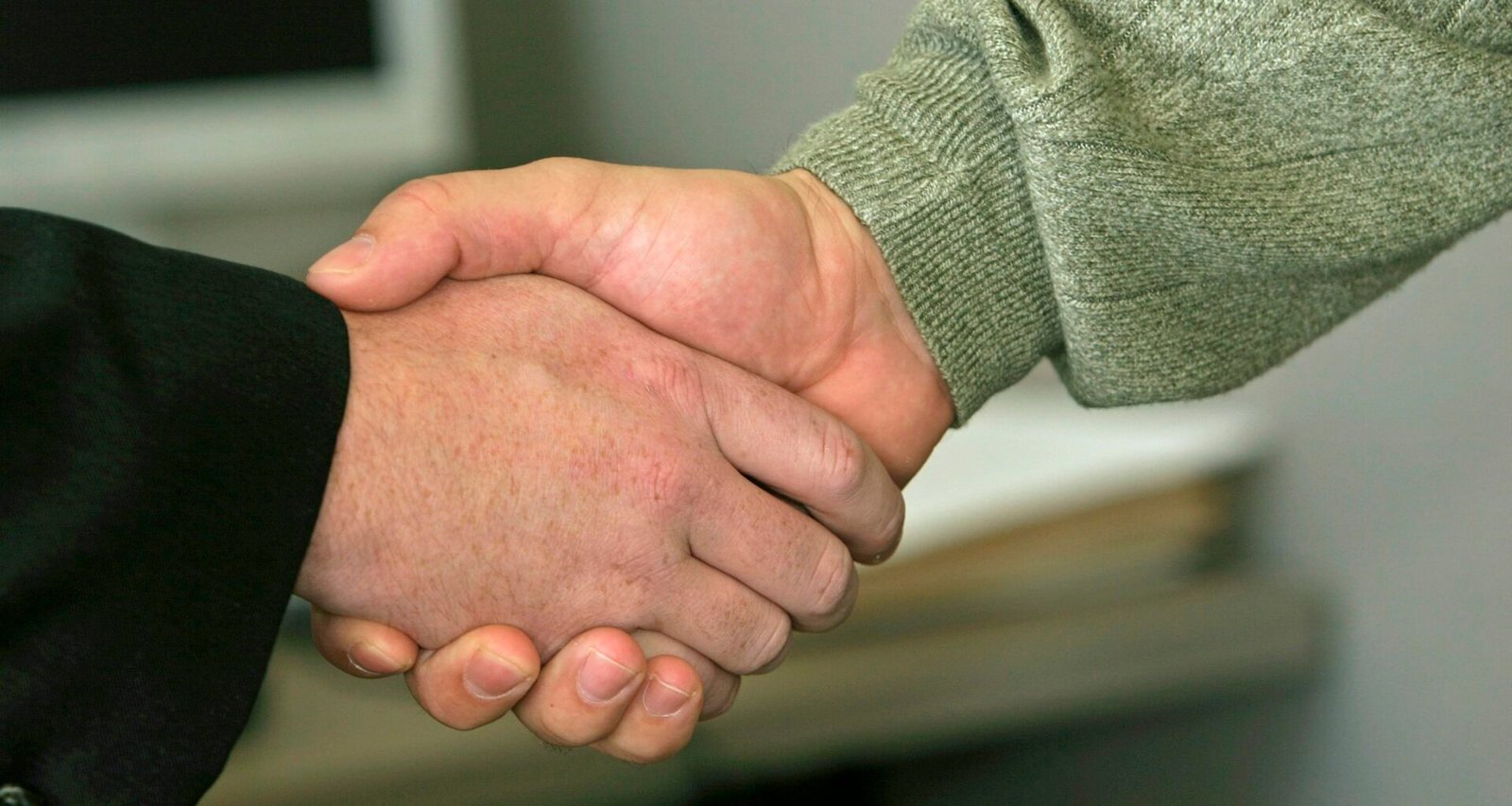 Nahaufnahme von zwei Menschen, die sich zum Abschluss einer geschäftlichen Vereinbarung die Hand geben.
