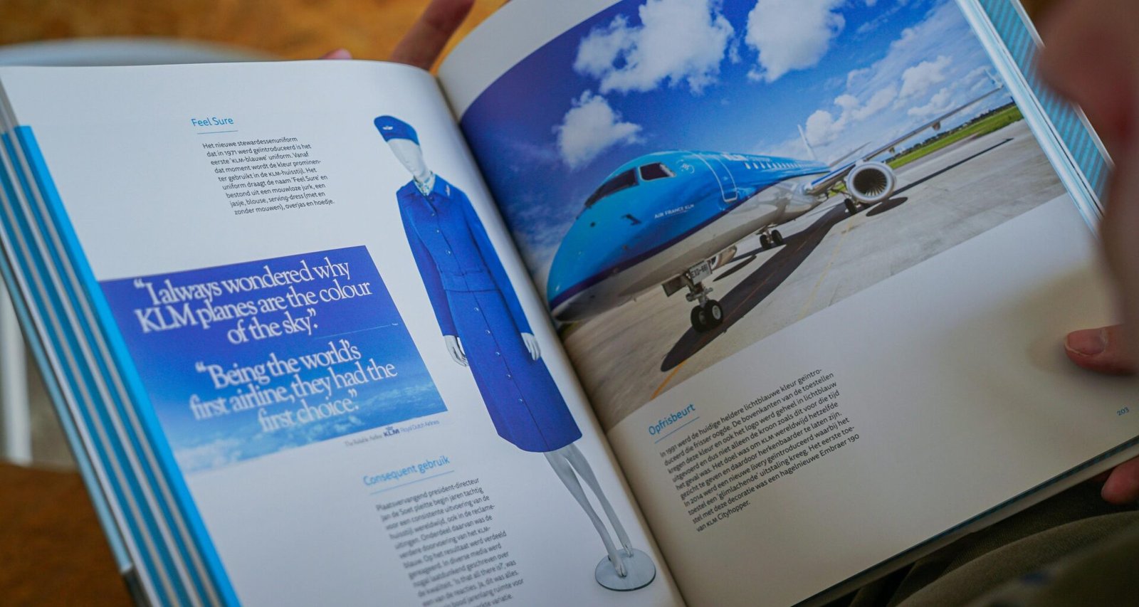 Eine Person hält ein geöffnetes Buch, auf dessen Seite ein Foto eines Flugzeugs zu sehen ist, Fokus auf Reisen und Technik