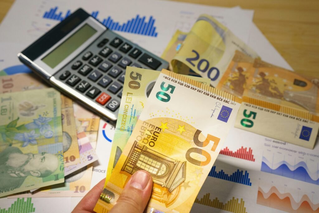 Eine Person hält mehrere Geldscheine in der Hand, neben einem Taschenrechner auf einem Tisch, Fokus auf Finanzverwaltung.