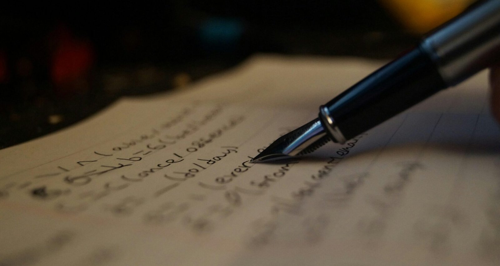 Eine Person schreibt mit einem Stift Notizen auf ein Blatt Papier am Schreibtisch, Fokus auf Hand und Papier