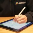 Eine Person schreibt mit einem Stift auf einem Tablet und nutzt dabei digitale Tools für Notizen oder Skizzen.
