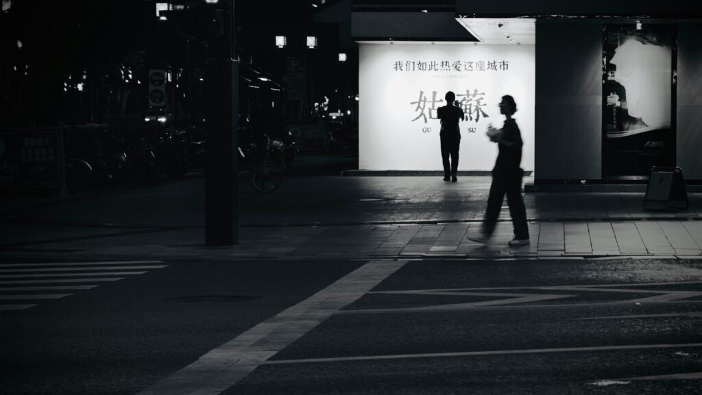 Eine Person läuft bei Nacht eine leere, von Straßenlaternen beleuchtete Straße entlang