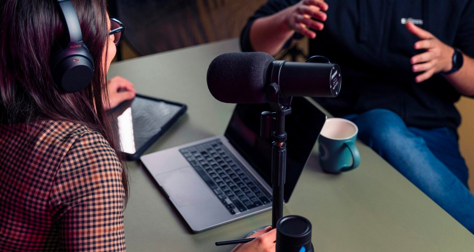 Person mit Kopfhörern sitzt an einem Schreibtisch und nutzt einen Laptop für Arbeit oder Online-Kommunikation