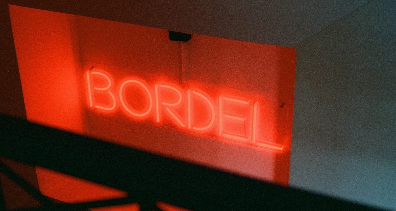 Leuchtendes rotes Neonzeichen mit dem Schriftzug bordil an einer Wand, fotografiert bei Nacht