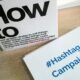 Eine Box mit der Aufschrift Hashtag Campaign steht auf einem Tisch und stellt Social-Media-Marketing dar.