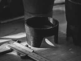 Eine silberne Schere liegt geöffnet auf einem hellen Holztisch und steht für sorgfältige Handarbeit