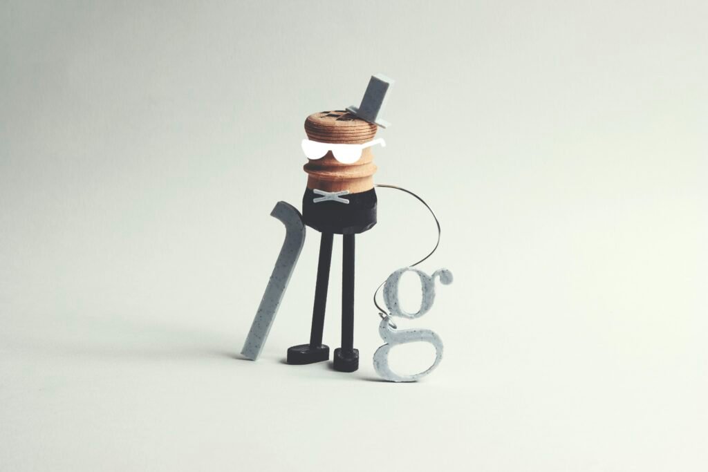 Eine ausgefallene Figur mit Stock und dem Buchstaben g als Accessoire, fotografiert vor neutralem Hintergrund