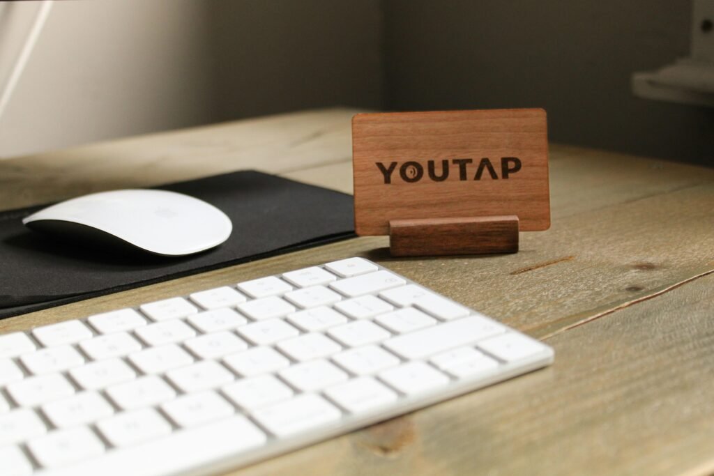 Eine schwarze Computertastatur und eine passende Maus auf einem weißen Schreibtisch, fotografiert aus der Vogelperspektive.