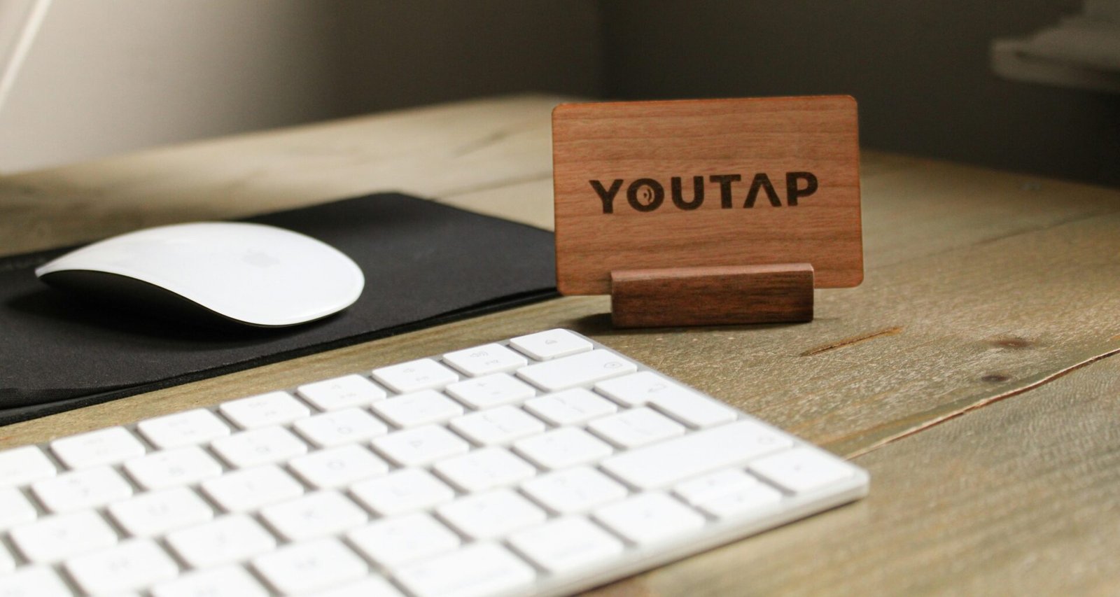 Eine schwarze Computertastatur und eine passende Maus auf einem weißen Schreibtisch, fotografiert aus der Vogelperspektive.