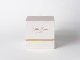 Weiße Box mit goldenen Akzenten steht auf weißem Hintergrund, minimalistisches Produktdesign gut erkennbar.