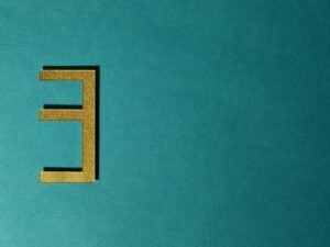 Die Ziffer 3 ist zentral vor einem einfarbigen, kräftig türkisfarbenen Hintergrund zu sehen.