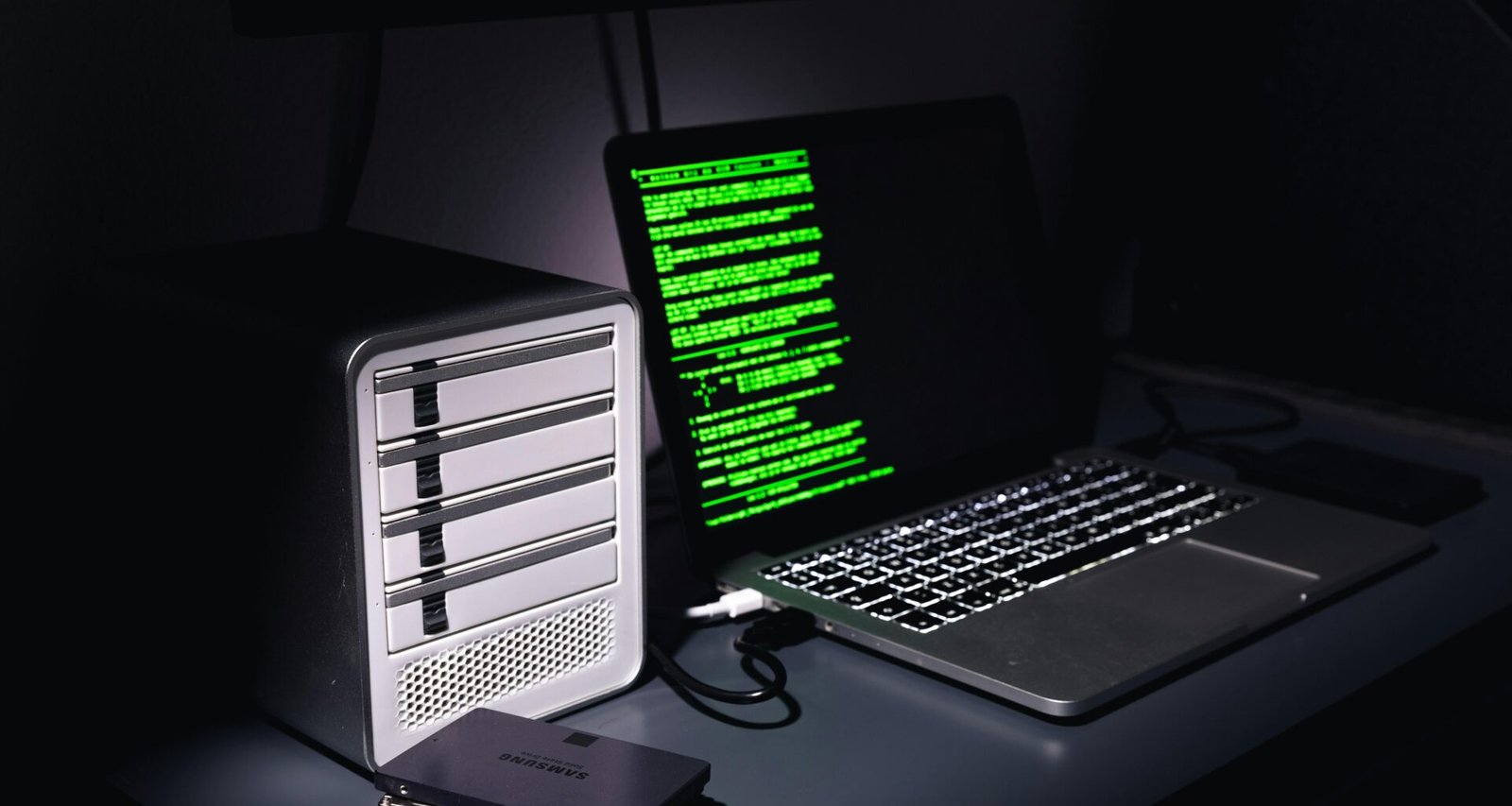 Ein Schreibtisch mit einem geöffneten Laptop neben einem klassischen Desktop-Computer in moderner Büro-Umgebung.