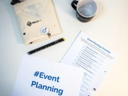 Kaffeetasse auf Holztisch mit Notizblock, Stift und Briefumschlag neben Laptop, ideales Setting für kreative Arbeit