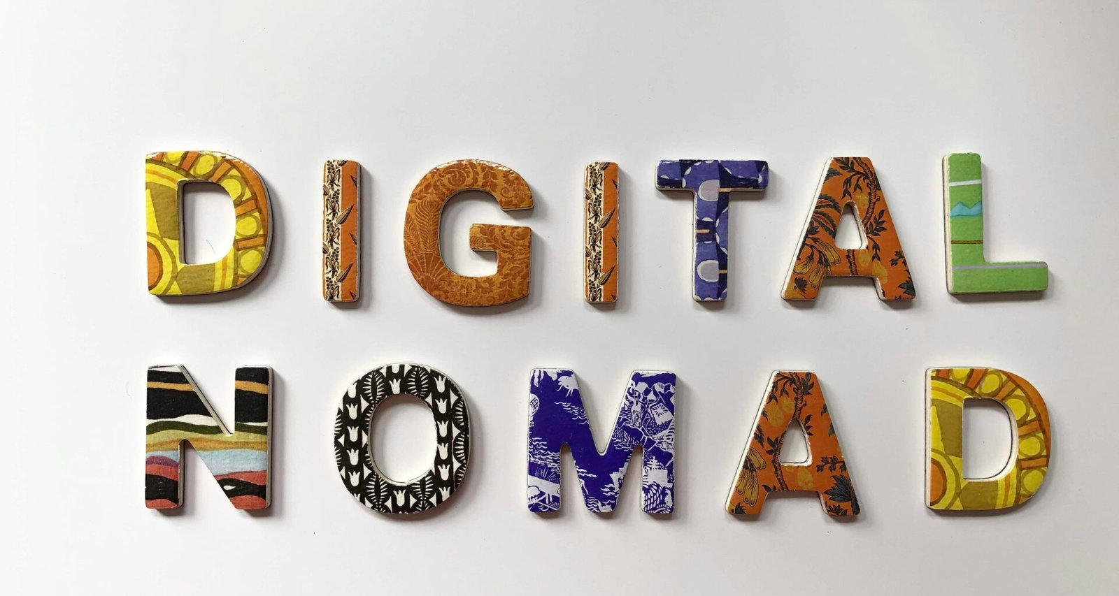 Bunte Buchstaben, die das Wort 'Digital Nomad' bilden, auf einer hellen Oberfläche arrangiert. Foto von Merakist.
