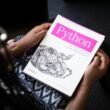 Schräg fotografiertes Python-Buch in Nahaufnahme auf einem Tisch, Fokus auf den Buchtitel, Umgebung unscharf dargestellt