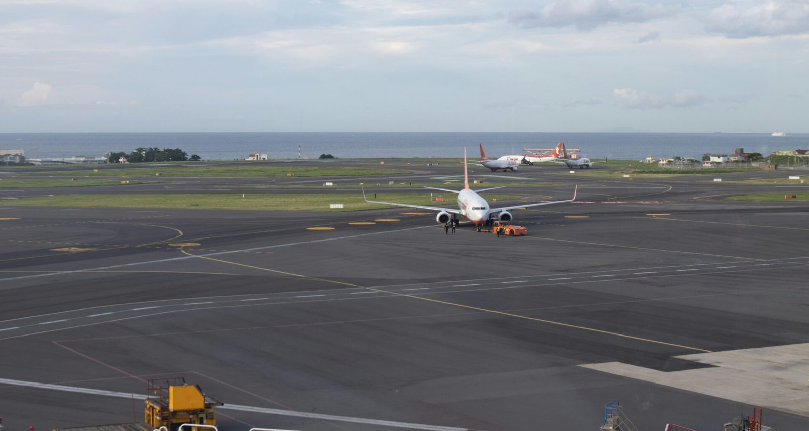 Mehrere Flugzeuge stehen am Flughafen auf dem Rollfeld in Küstennähe mit Blick auf das Meer im Hintergrund.